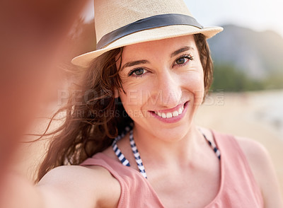 Buy stock photo Portrait of a happy young woman taking a selfie on a tropical beach