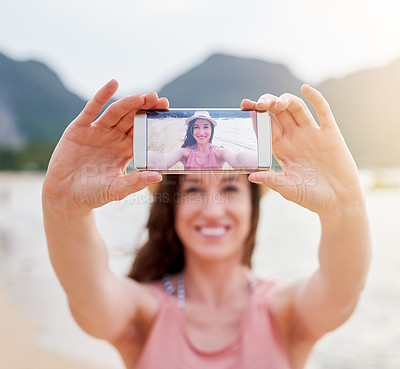Buy stock photo Shot of a happy young woman taking a selfie with her phone on a tropical beach