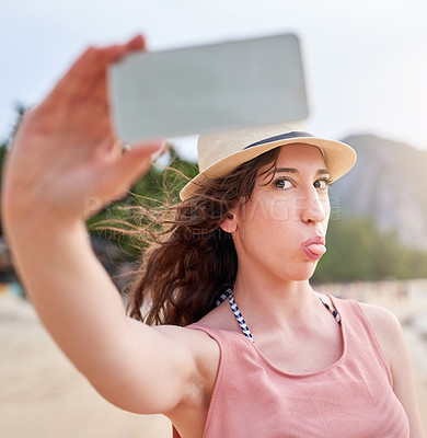 Buy stock photo Shot of a happy young woman taking a selfie with her phone on a tropical beach