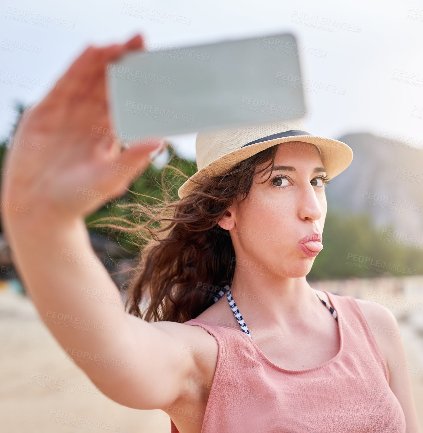 Buy stock photo Shot of a happy young woman taking a selfie with her phone on a tropical beach