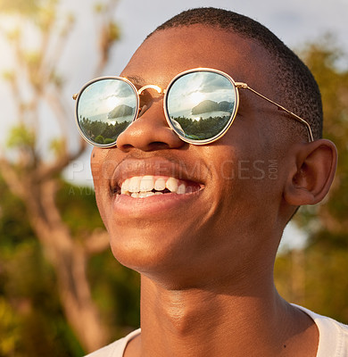 Buy stock photo Shot of a happy young man wearing sunglasses while admiring the view outside