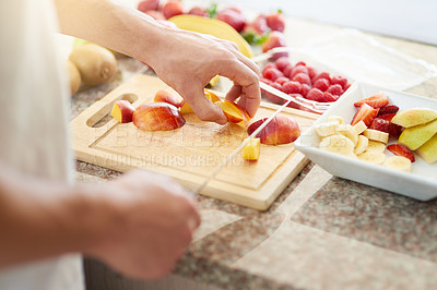 Buy stock photo Cropped shot of a young man making a fruit salad in his kitchen