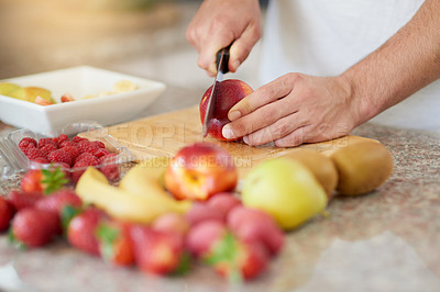 Buy stock photo Cropped shot of a young man making a fruit salad in his kitchen