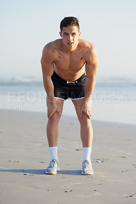 Buy stock photo Full length portrait of a handsome young man looking tired after a run on the beach