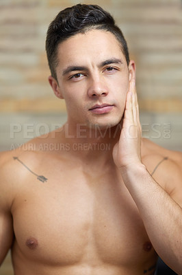 Buy stock photo Shot of a young man touching his face after shaving