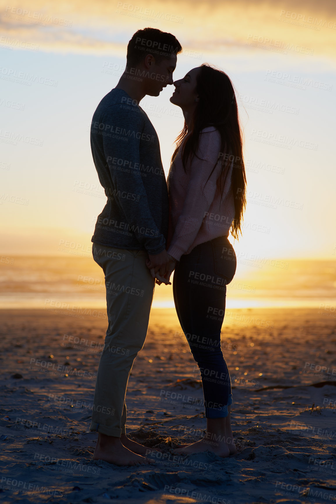 Buy stock photo Silhouette shot of a young couple on the beach
