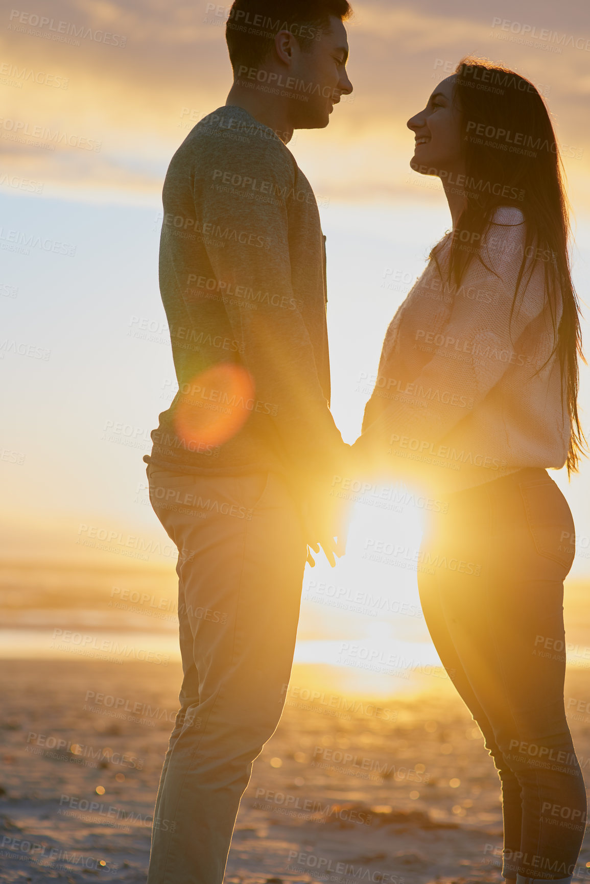 Buy stock photo Shot of a young couple at the beach at sunset