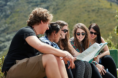 Buy stock photo Shot of a group of friends reading a map together while out on a roadtrip