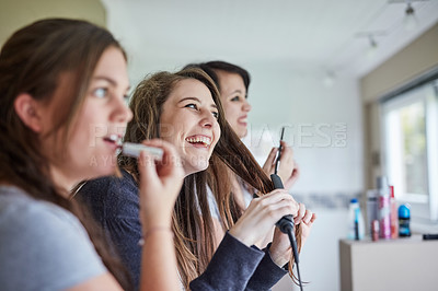 Buy stock photo Cropped shot of three young friends putting on makeup and styling their hair in the bathroom