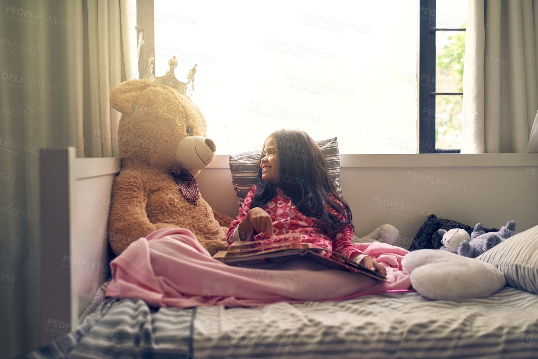 Buy stock photo Shot of an adorable little girl reading a book with her teddy bear in bed