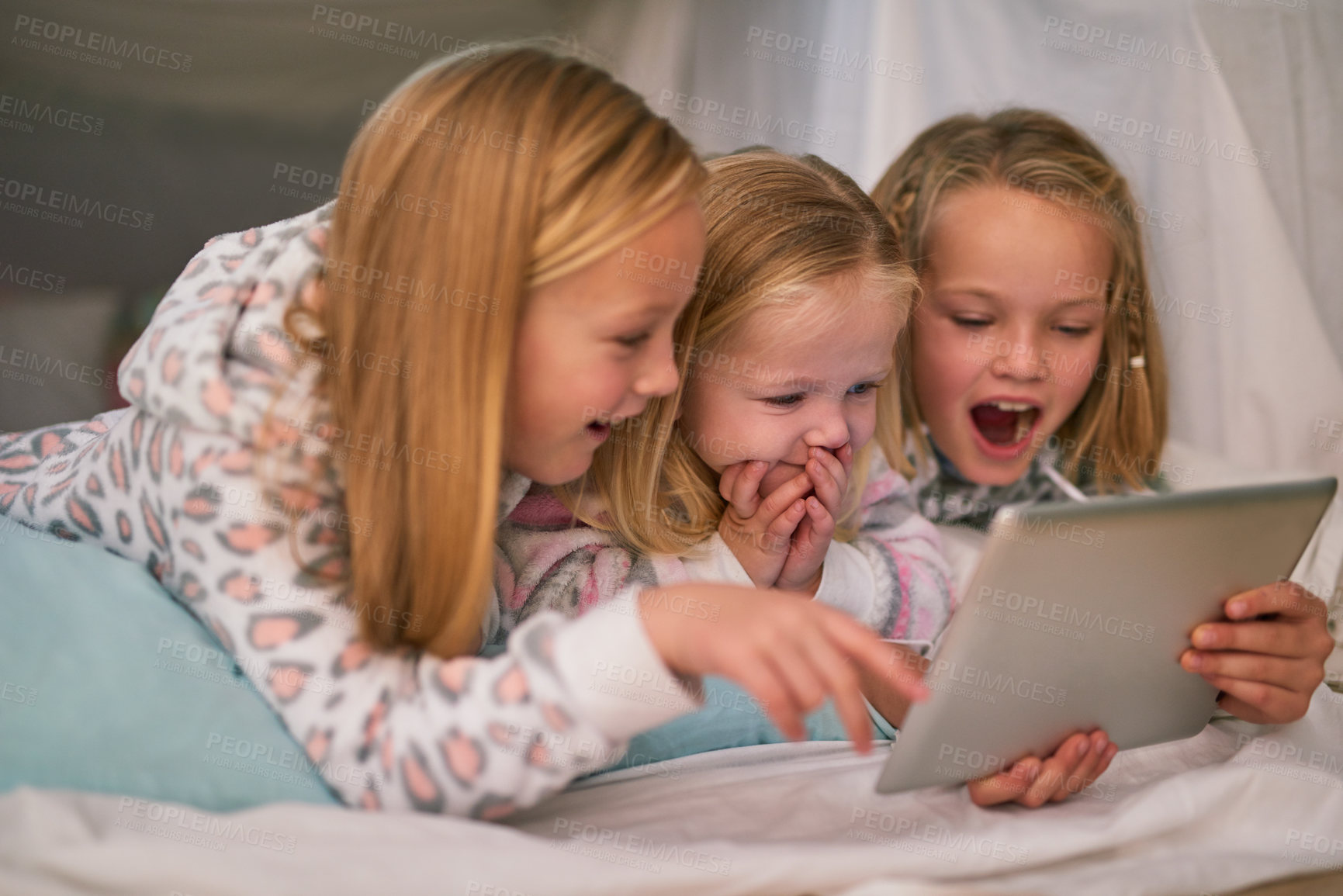 Buy stock photo Cropped shot of three little sisters using a digital tablet before bedtime