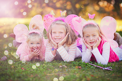 Buy stock photo Outdoor, fairy and portrait of sisters lying in field with wings for dress up, princess outfit or cosplay. Bokeh, nature and young children with smile for fantasy play, childhood or halloween costume