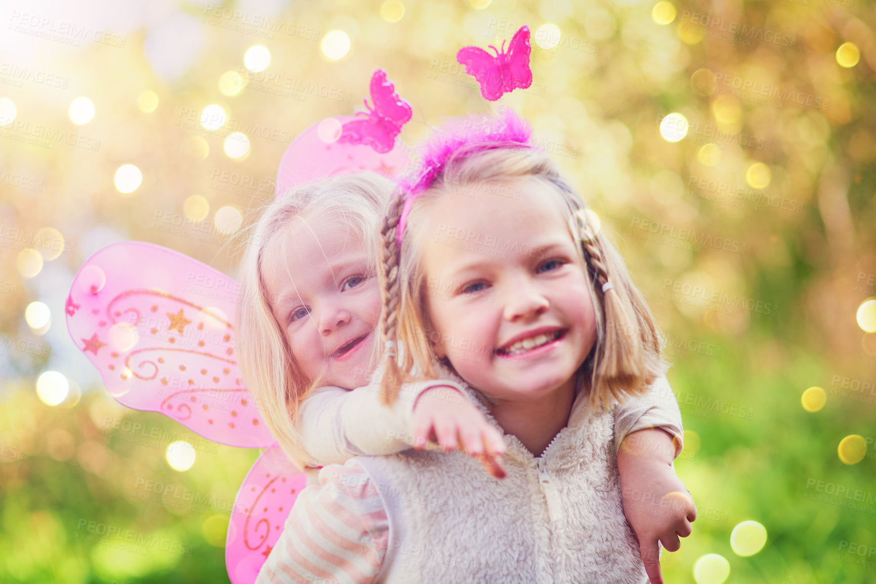 Buy stock photo Children, fairy and portrait of piggyback in outdoor park with wings for dress up, princess outfit or cosplay. Bokeh, nature and sisters with smile for fantasy play, childhood or halloween costume