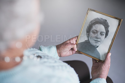 Buy stock photo Cropped shot of a senior woman looking at an old black and white photo of a woman