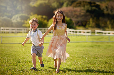 Buy stock photo Portrait of a cute brother and sister running across a field while holding hands