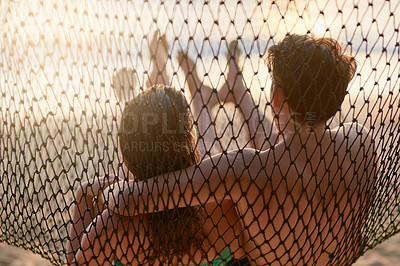 Buy stock photo Rear view shot of a young couple relaxing on a hammock at the beach