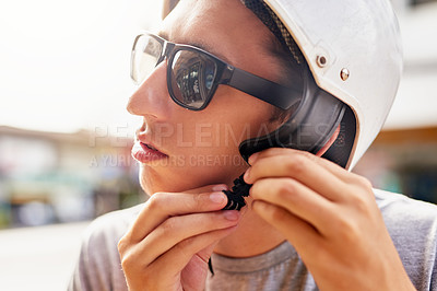 Buy stock photo Shot of a young man strapping on a bike helmet outside