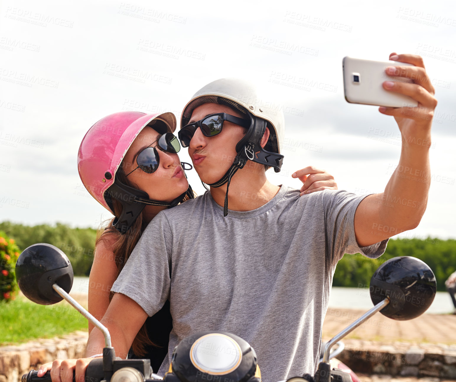 Buy stock photo Shot of a young couple taking a selfie together while out for a ride on a scooter
