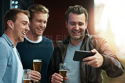Buy stock photo Shot of a group of friends enjoying a beer together while standing on a balcony together