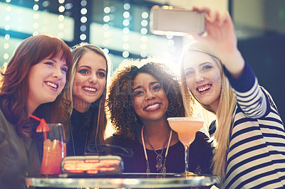 Buy stock photo Shot of a group of happy friends taking a selfie while enjoying cocktails