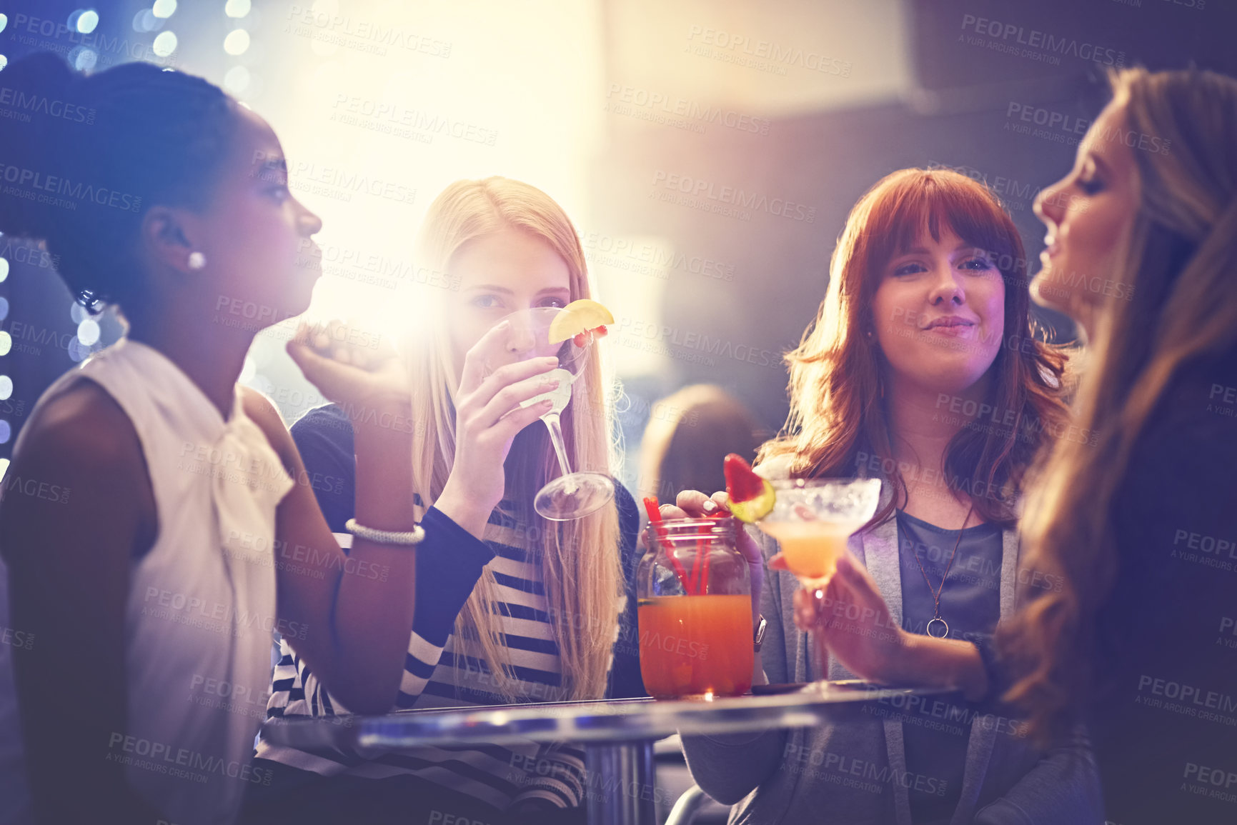 Buy stock photo Shot of a group of friends relaxing with cocktails in a nightclub
