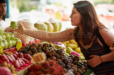 Buy stock photo Shot of an attractive young woman looking at fruit in a foreign grocery store