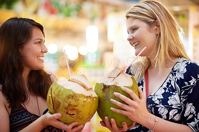 Buy stock photo Cropped shot of two young women drinking from coconuts in a foreign grocery store