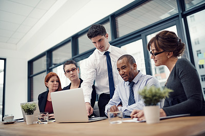 Buy stock photo Cropped shot of group of businesspeople using a laptop together during a meeting in an office