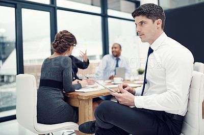 Buy stock photo Cropped shot of a businessman using a digital tablet during a meeting with his colleagues
