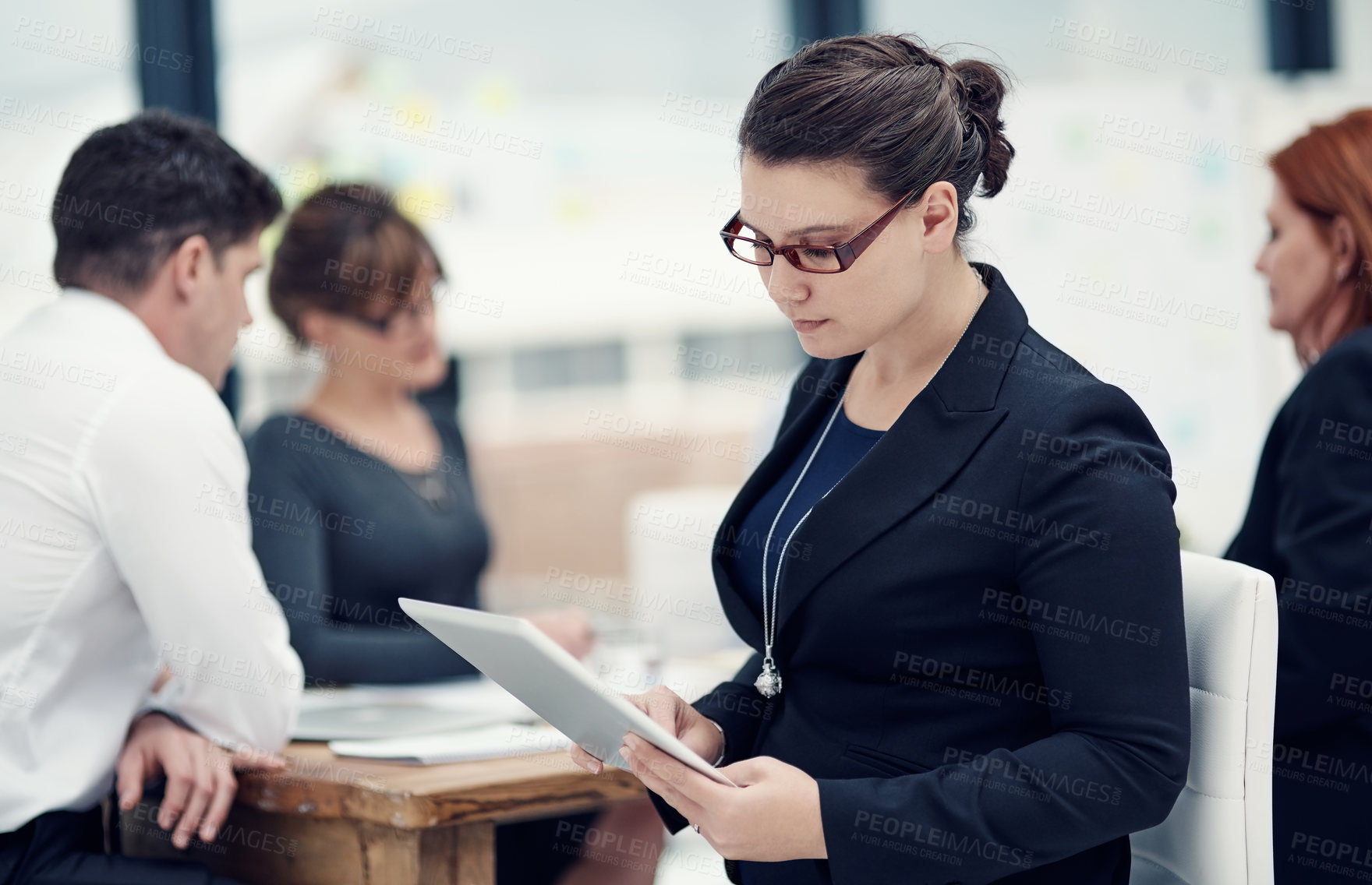 Buy stock photo Cropped shot of a businesswoman using a digital tablet during a meeting with her colleagues