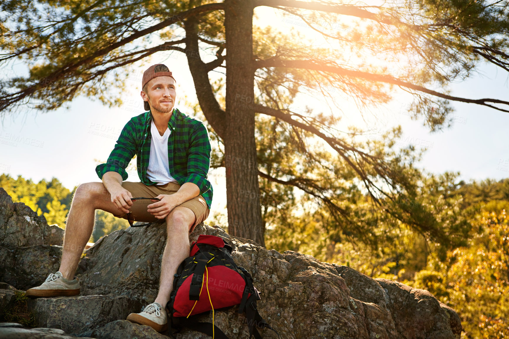 Buy stock photo Shot of a handsome young man hiking while on an overseas trip