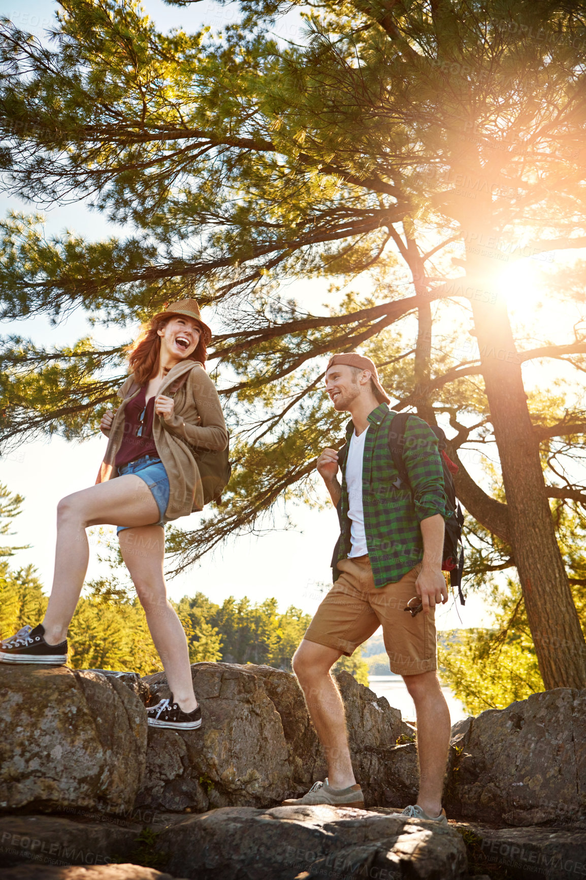 Buy stock photo Sunshine, hiking and couple walking with trees, nature and adventure holiday in outdoor park. Trekking, man and woman on sustainable travel vacation together in woods with smile, rocks and happy date