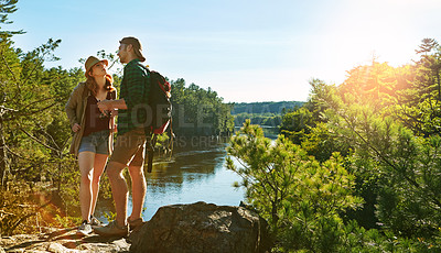 Buy stock photo Blue sky, hiking and couple on cliff at lake on adventure holiday in mountain with trees, sun, and water. Trekking, man and woman on travel vacation together at river, forest or outdoor for climbing