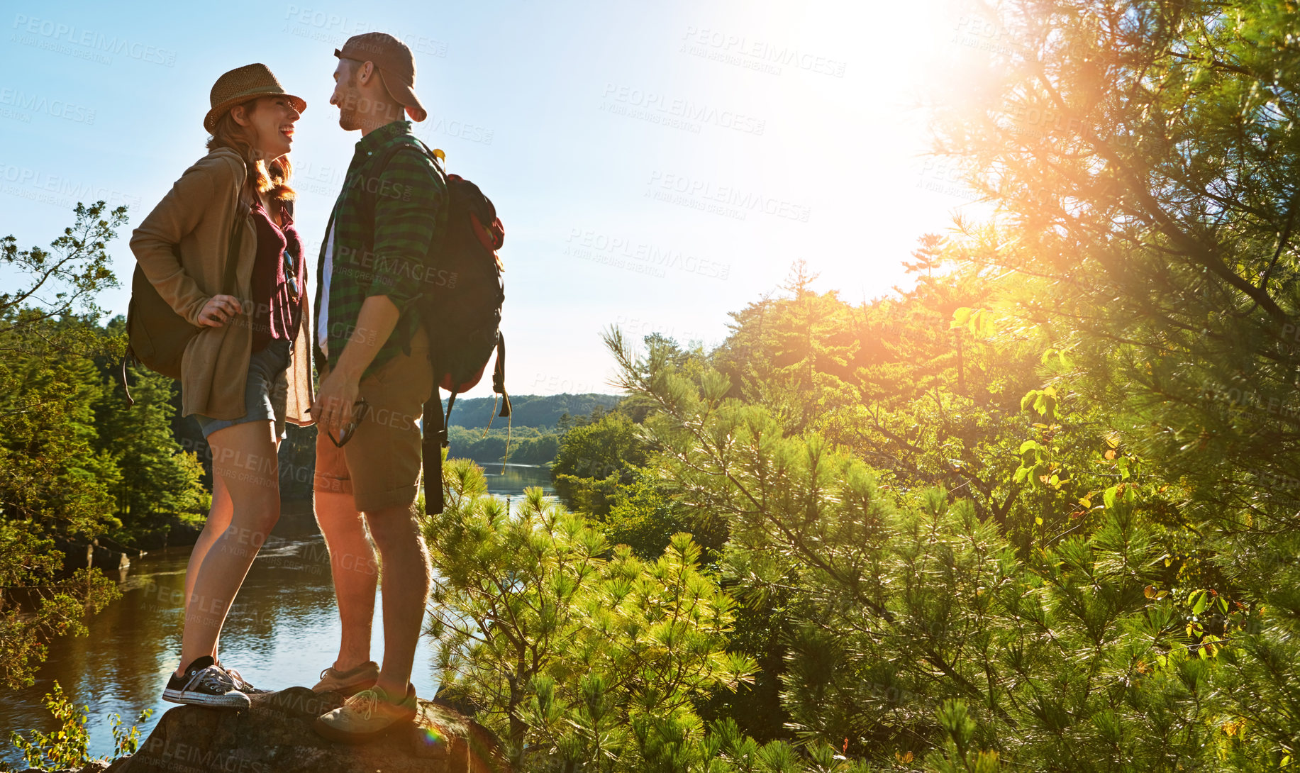 Buy stock photo Nature, hiking and couple on cliff at water on adventure holiday in mountain with trees, sun, and lake. Trekking, man and woman on travel vacation together at river, forest or outdoor climbing park