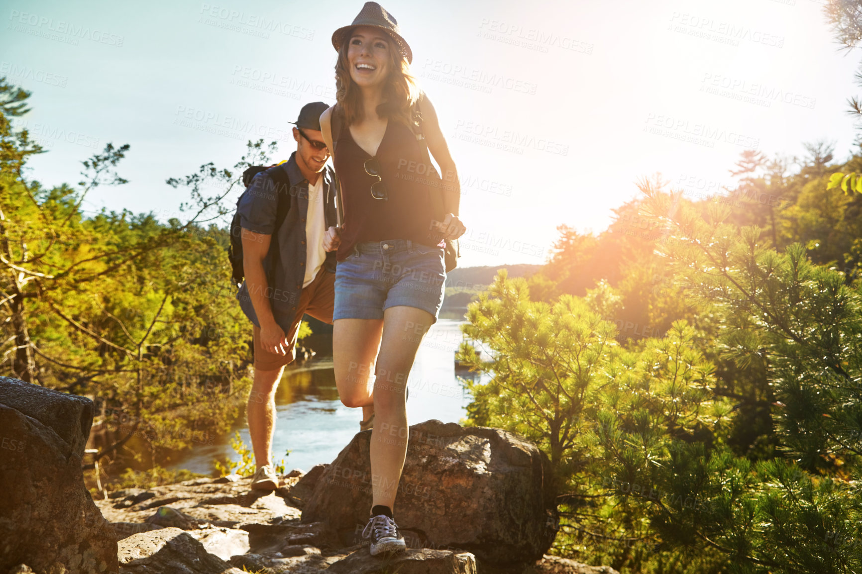 Buy stock photo Nature, hiking and couple walking with river, blue sky and adventure holiday in countryside. Trekking, man and woman on sustainable travel vacation together in park with trees, water and outdoor date