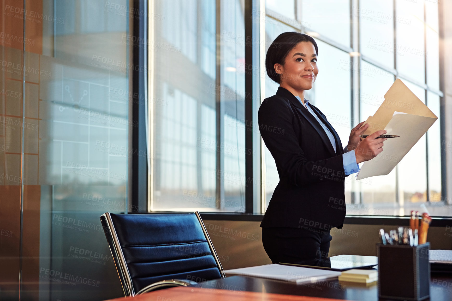 Buy stock photo Shot of a young female lawyer standing by her desk in the office