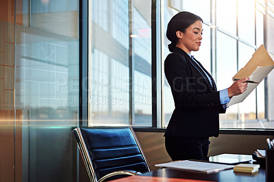 Buy stock photo Shot of a young female lawyer standing by her desk in the office