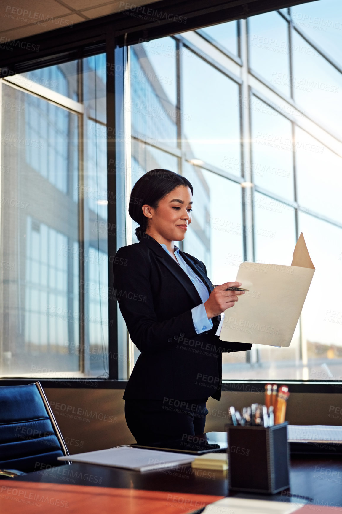 Buy stock photo Shot of a young female lawyer standing by her desk in the office