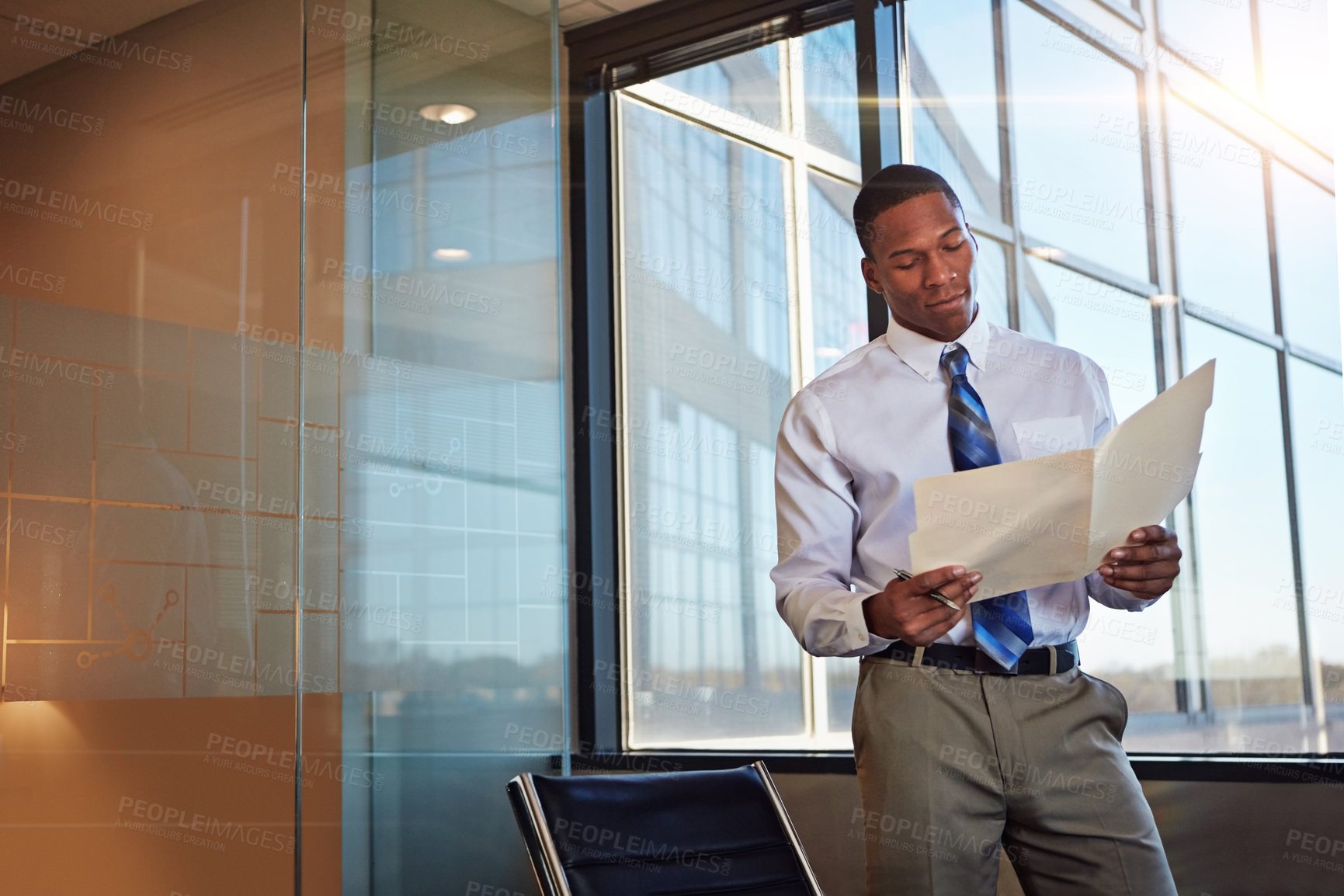 Buy stock photo Shot of a young male lawyer standing by his desk in the office