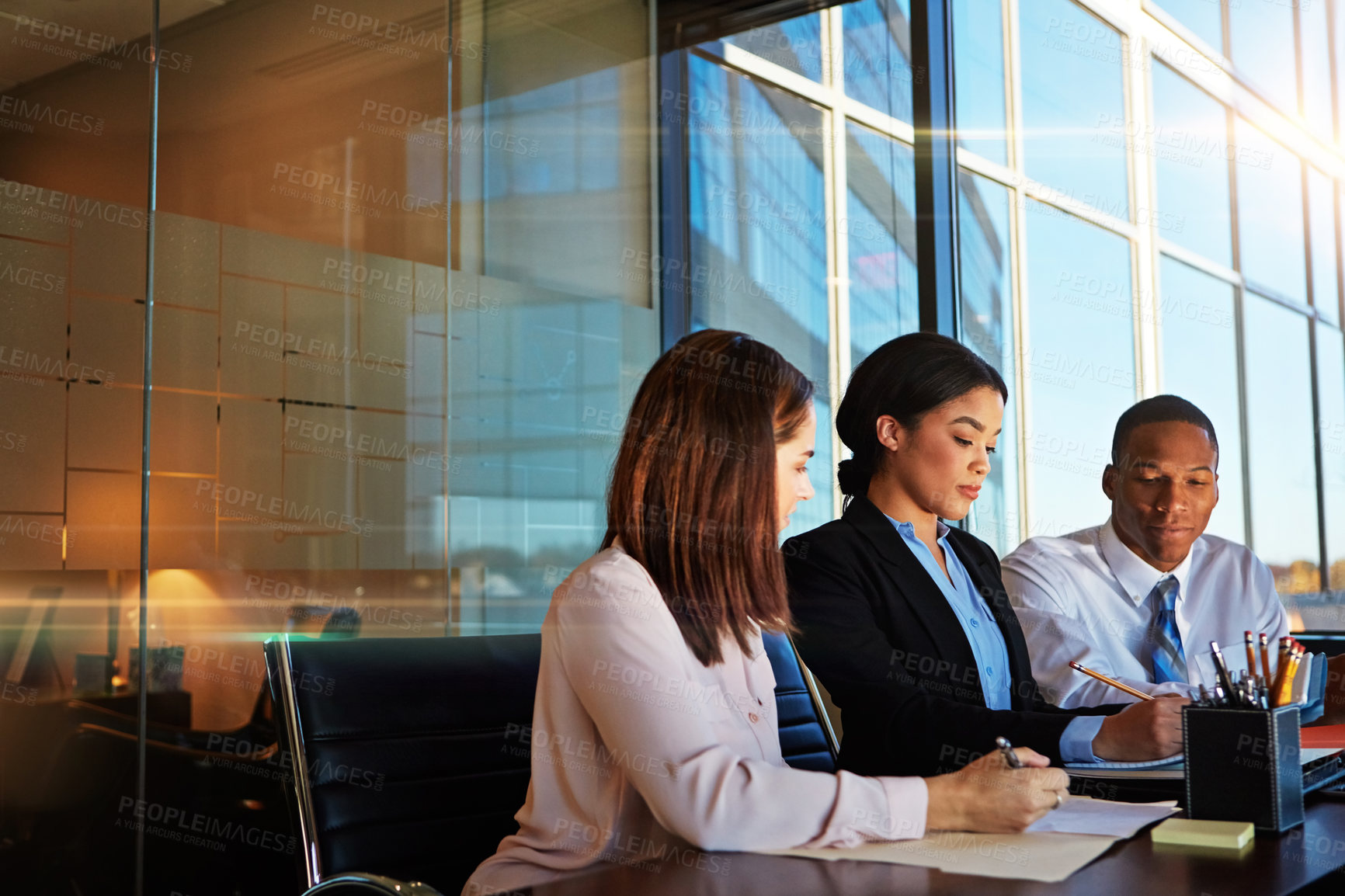 Buy stock photo Cropped shot of three young businesspeople meeting in the boardroom