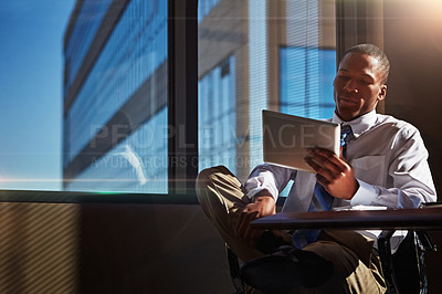 Buy stock photo Shot of a businessman using his digital tablet at his desk