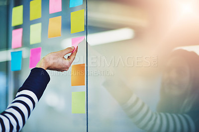 Buy stock photo Cropped shot of a woman pasting notes on glass during a brainstorming session at work