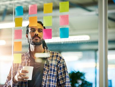 Buy stock photo Shot of a young man having a brainstorming session with sticky notes at work
