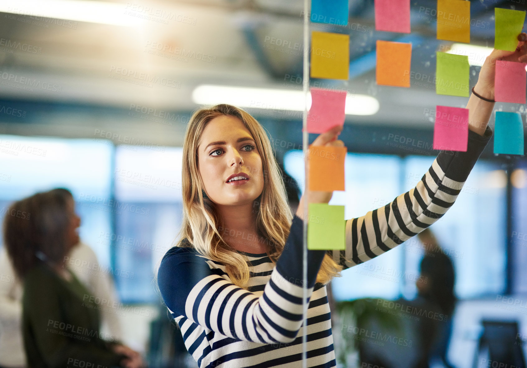 Buy stock photo Shot of a young woman having a brainstorming session with sticky notes at work