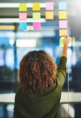 Buy stock photo Rearview shot of a woman having a brainstorming session with sticky notes at work