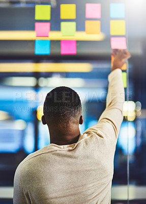 Buy stock photo Rearview shot of a man having a brainstorming session with sticky notes at work