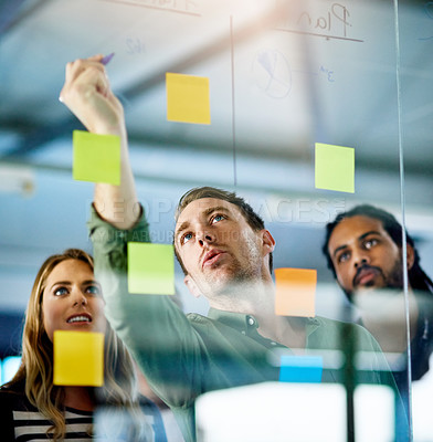 Buy stock photo Shot of colleagues having a brainstorming session with sticky notes at work