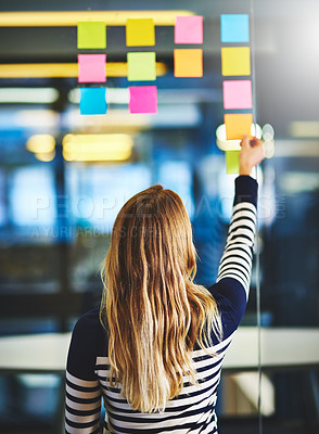 Buy stock photo Rearview shot of a woman having a brainstorming session with sticky notes at work