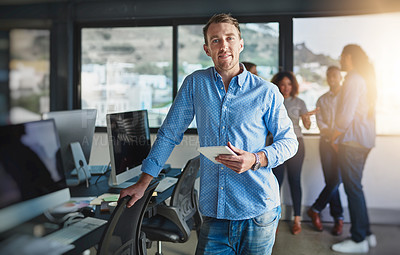 Buy stock photo Portrait of a handsome young designer standing in the office with his colleagues in the background