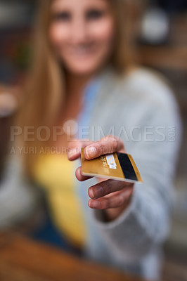 Buy stock photo Cropped shot of a young woman holding her credit card back for payment in a cafe